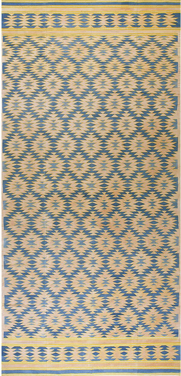 Blue and tan low-profile rug with a repeating geometric zigzag field and striped end borders with yellow accents.