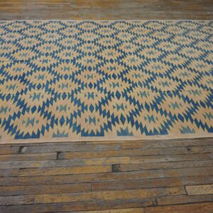 Blue and beige diamond pattern flatweave rug on rustic wide plank wood floor.