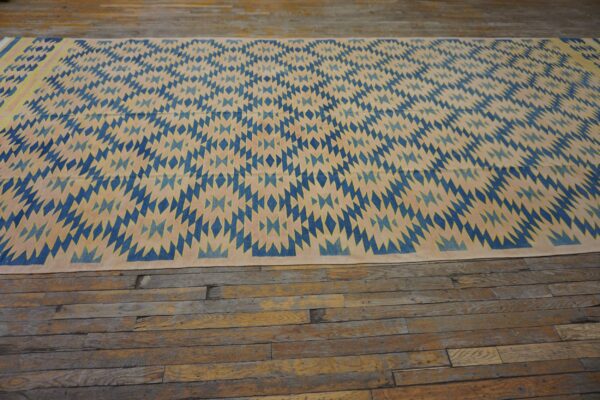 Blue and beige diamond pattern flatweave rug on rustic wide plank wood floor.