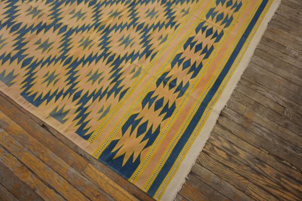 Geometric blue and yellow rug featuring jagged motifs and a striped border rests on weathered wood planks.