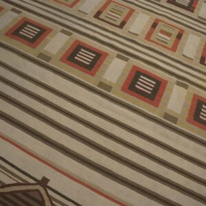 Geometric flatweave rug featuring wide stripes and diamond motifs in beige, brown, and burnt orange.