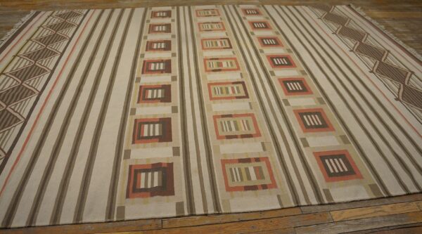 Cream and brown striped flatweave rug with repeating geometric columns and zigzag borders on wood flooring.
