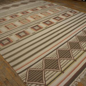Flatweave rug featuring bold stripes and repeating squares in cream, brown, and peach on wood floors.