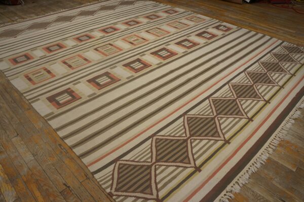 Flatweave rug featuring bold stripes and repeating squares in cream, brown, and peach on wood floors.