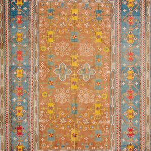 Rust and blue geometric rug with yellow and red patterns displayed on distressed wooden flooring.