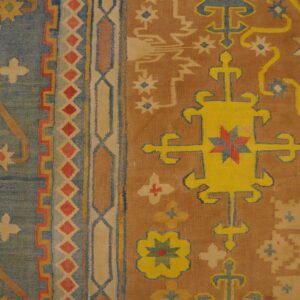 Colorful flatweave rug displaying geometric medallions and complex borders in blue, yellow, and rust tones.