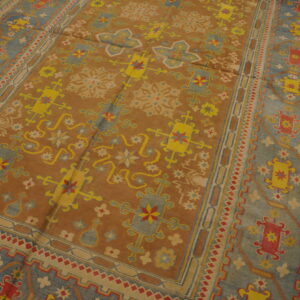 Geometric patterned rug in brown, blue, yellow, and red colors resting on distressed wood flooring.