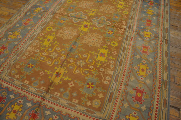 Geometric patterned rug in brown, blue, yellow, and red colors resting on distressed wood flooring.