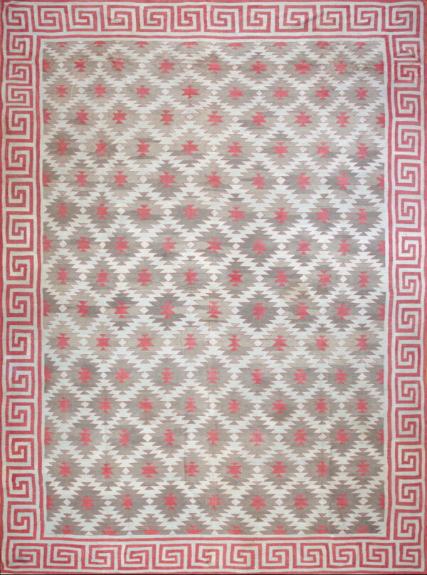 Flatweave rug with pink, grey, and white southwestern patterns and a coral greek key border.