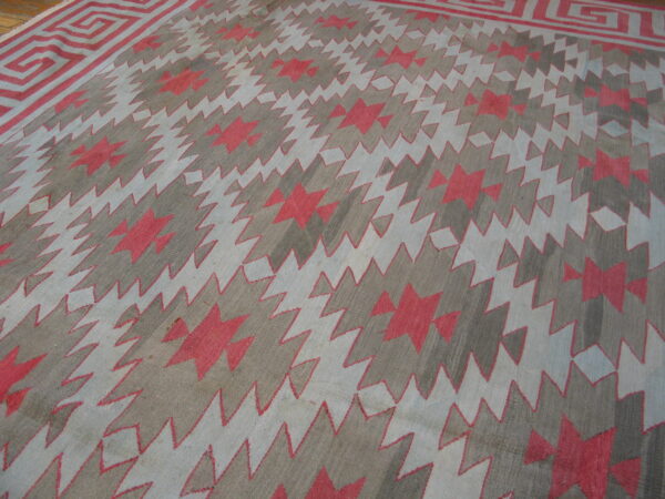 Geometric rug featuring a zigzag field and greek key border in gray, light blue, and coral red.