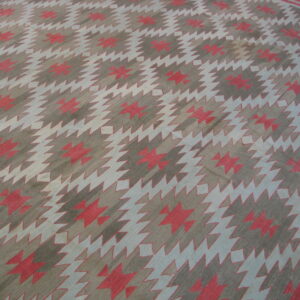 Geometric flatweave rug featuring repeating stepped diamonds in taupe, light blue, and faded coral colors.