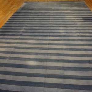 Low-pile rug with alternating blue and gray horizontal stripes covering a light brown wood floor.