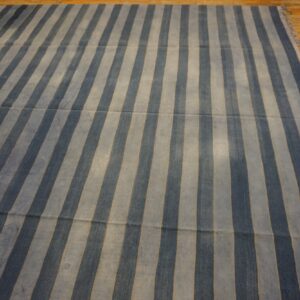 Navy and pale blue striped rug with a low texture, lying on plank hardwood flooring.