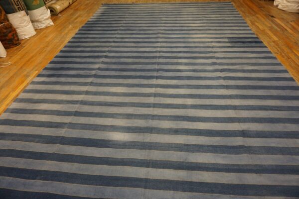 Wide rug with alternating dark blue and pale blue horizontal stripes on wood flooring.