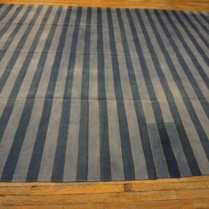 A low-pile rug with alternating dark blue and light blue vertical stripes covers rustic wood plank flooring.