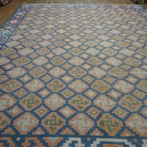 Geometric flatweave rug in blue, peach, gray, and green on rustic hardwood flooring.