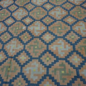 Stepped geometric rug pattern in dark blue, peach, gray, olive, and yellow colors.
