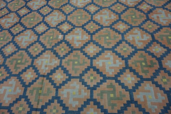 Stepped geometric rug pattern in dark blue, peach, gray, olive, and yellow colors.