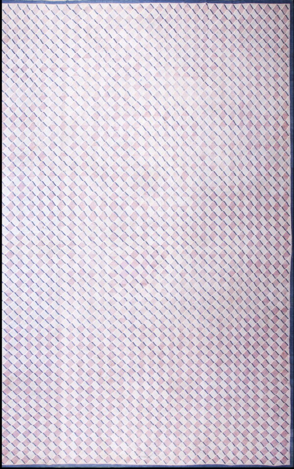 A low-pile rug features a diagonal geometric cube pattern in pink, white, and navy blue with a solid border.