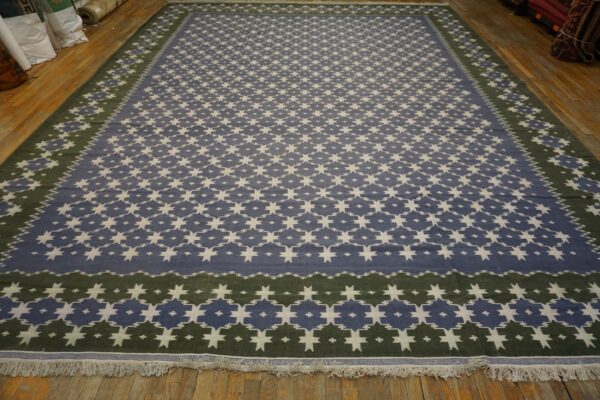 A large blue and white geometric rug with a dark green border rests on wooden floorboards.