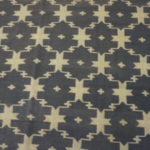 Geometric flatweave rug featuring interlocking beige star motifs on a dark slate background.