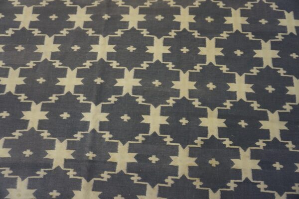 Geometric flatweave rug featuring interlocking beige star motifs on a dark slate background.