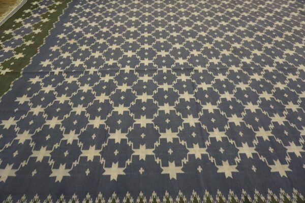 Flatweave rug in blue and cream with a geometric pattern and an adjoining olive green border.