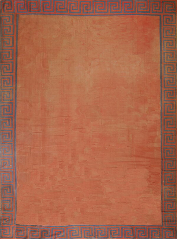 Distressed terracotta rug featuring a greek key border pattern in muted blue and the main field color.