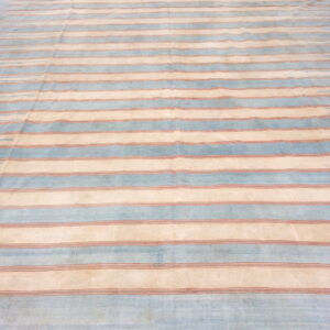 Low-pile rug with alternating pale blue and cream horizontal stripes featuring thin reddish lines.