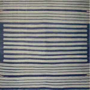 A large flat-weave rug with alternating wide bands of navy blue and off-white stripes lies on a wood floor.