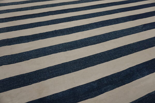 Low-pile rug with broad diagonal stripes in dark blue and slightly grayish off-white.