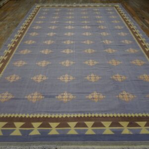 Blue rug with repeating orange lozenges and a thick geometric border of brown and pale yellow triangles.