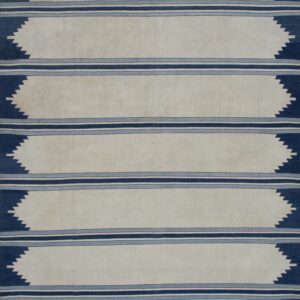 Off-white flatweave rug with vertical triple blue stripes and dark blue serrated zigzags on wood flooring.