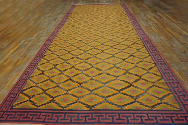 Yellow flatweave runner with diamond and greek key patterns rests on light hardwood floors.