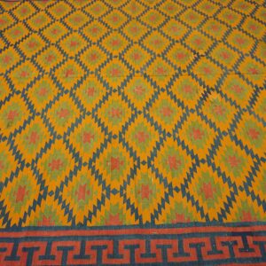 Yellow rug featuring blue and green geometric patterns and a detailed meander border at the bottom.
