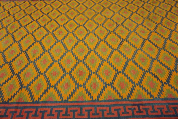 Yellow rug featuring blue and green geometric patterns and a detailed meander border at the bottom.