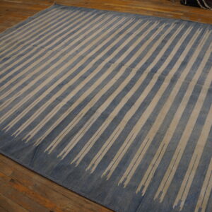 Large blue and beige rug with fading diagonal stripes covers rustic wood planks.