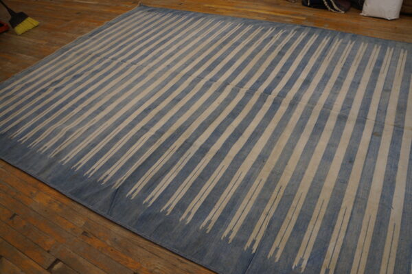 Large blue and beige rug with fading diagonal stripes covers rustic wood planks.