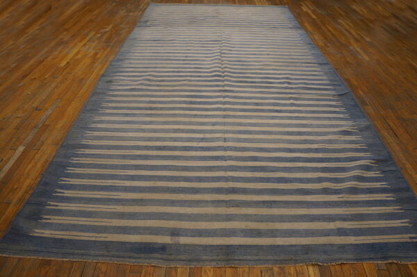 Blue and tan flatweave rug with irregular horizontal stripes resting on hardwood flooring.