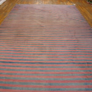 Large flatweave rug with alternating red and blue horizontal stripes covers a polished wood floor.