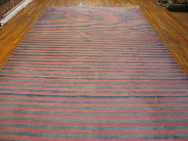 Large flatweave rug with alternating red and blue horizontal stripes covers a polished wood floor.