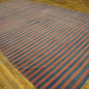 A large blue and faded reddish-pink striped rug covers the worn, light hardwood floor.