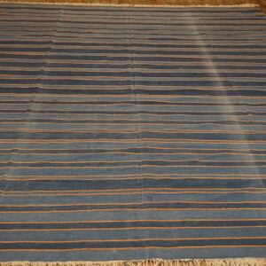 Striped blue rug with contrasting thin orange horizontal lines rests on light brown hardwood flooring.