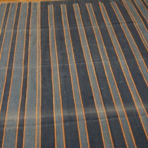 Dark blue and grey striped rug with thin orange accents lying on a wood floor.