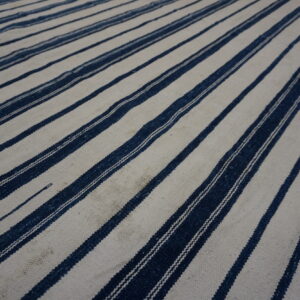 Textured low-pile rug displaying wide cream bands alternating with narrow dark blue vertical stripes.