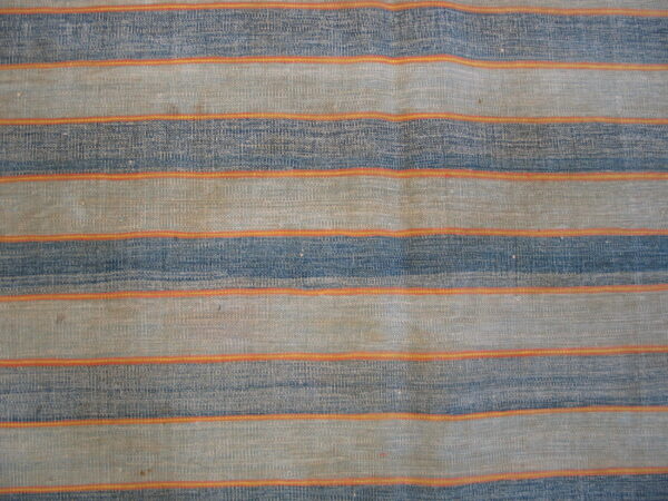 Close-up of a woven rug with wide horizontal stripes of indigo and tan, separated by narrow orange bands.