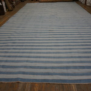 Wide, low-pile rug with irregular blue and pale blue stripes laid on shiny wood plank flooring.