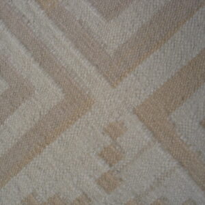 Geometric rug texture showing a large interlocking pattern in contrasting light beige and ivory tones.