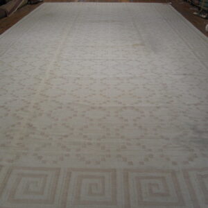Monochromatic beige rug featuring an overall scattered geometric design and a Greek key motif border.