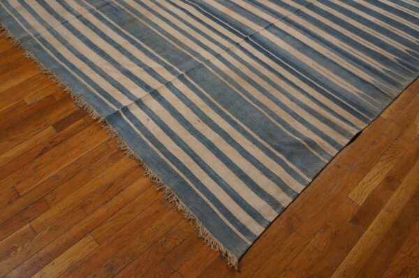 A flatwoven rug with blue and beige stripes covers a section of the brown plank floor.